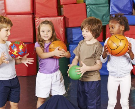Kinder spielen mit verschiedenen Bällen in der Turnhalle einer Vorschule